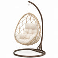 Sedia sospesa in rattan con struttura in metallo e cuscini beige